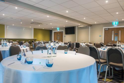 a conference room with white tables and chairs and a screen at Holiday Inn Lancaster by IHG in Lancaster