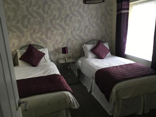 two beds in a hotel room with purple pillows at Highland Escape in Fort William