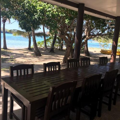 a wooden table and chairs with the beach in the background at Long Beach Escape in Vuake