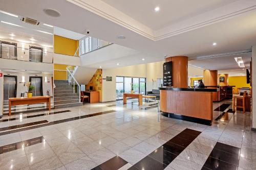 a lobby with a staircase and a reception desk at Slim Curitiba Alto da XV by Slaviero Hotéis in Curitiba
