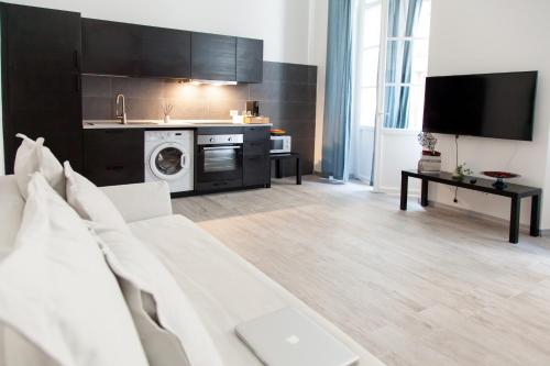 a living room with a white couch and a kitchen at NIU LUX Apartments in Genoa