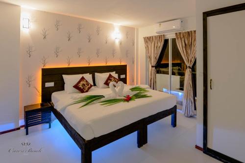 a bedroom with a bed with a flower on it at Crown Beach Hotel Maldives in Dhiffushi