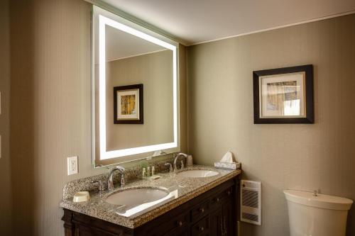 a bathroom with two sinks and a large mirror at Holiday Inn Sudbury, an IHG Hotel in Sudbury