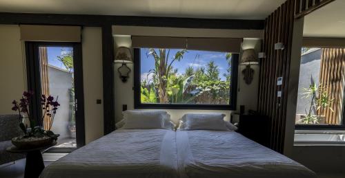 a bedroom with a large bed and two windows at Hotel Boutique Varadero in Zahara de los Atunes