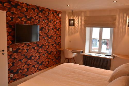 a hotel room with a bed and a television on a wall at LA GLORIETTE in Marche-en-Famenne