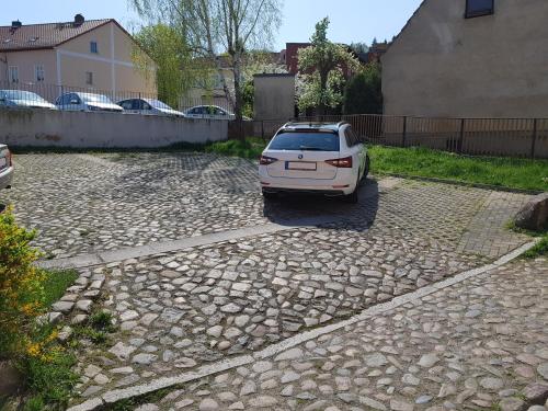 a white car parked on a stone driveway at Hotel-Garni "Zum Löwen" in Bad Freienwalde