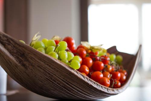 a wooden bowl of tomatoes and grapes on a table at Alpen-Herz Romantik & Spa - Adults Only in Ladis