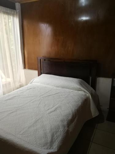 a bed with a wooden headboard and a window at Bijagua paradise Río Celeste in Bijagua