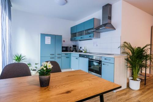 een keuken met blauwe kasten en een houten tafel bij Hotel sleep-station in Börnsen