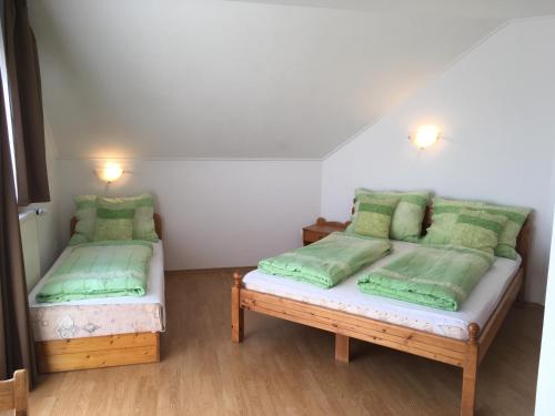 two beds in a room with green pillows at Balaton Vendégház in Balatonfüred