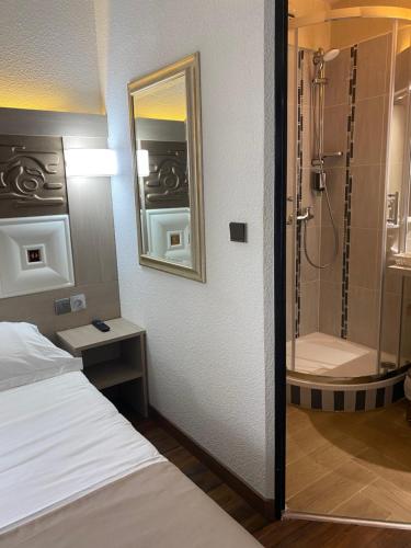 a bedroom with a shower and a bed and a mirror at Kimotel Epône-Flins in Épône