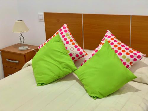 dwie limonkowo-zielone i różowe poduszki na łóżku w obiekcie Apartamento San Francisco w mieście Santa Cruz de la Palma