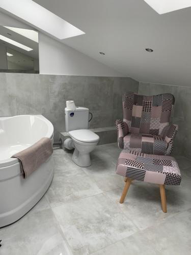 a bathroom with a tub and a chair and a toilet at Look of Dreams - Apartamenty Słoneczny i Księżycowy in Będzin