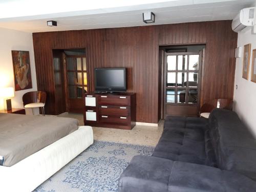 a bedroom with a bed and a couch and a tv at Casa con Palmera - Port in Valencia