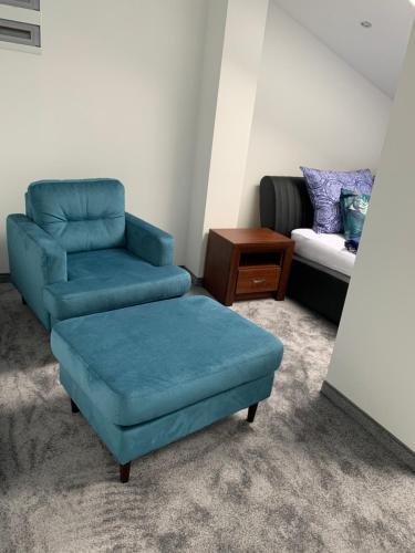 a living room with a blue chair and a couch at Look of Dreams - Apartamenty Słoneczny i Księżycowy in Będzin