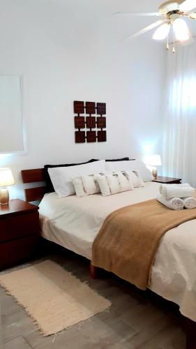 a bedroom with a bed with white sheets and a ceiling fan at MNG-Apart Mareverde Costa Adeje- Las Americas in Adeje