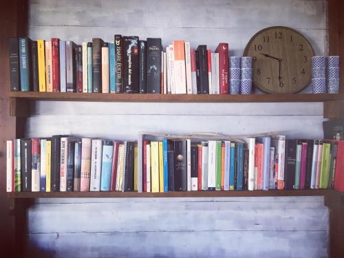 Uma estante com livros e um relógio. em Residence Cort'e Accas em Bari Sardo