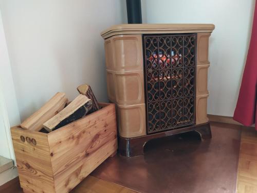 a woodburning stove with a wooden box next to it at CASA IDA - ClPAT 22253 in Tregiovo