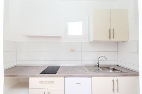 a white kitchen with a sink and white cabinets at Knezovicapartments in Živogošće