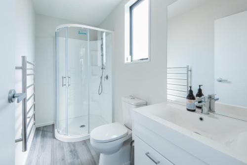 Un baño blanco con inodoro y ducha. en Simply Stunning, en Wanaka