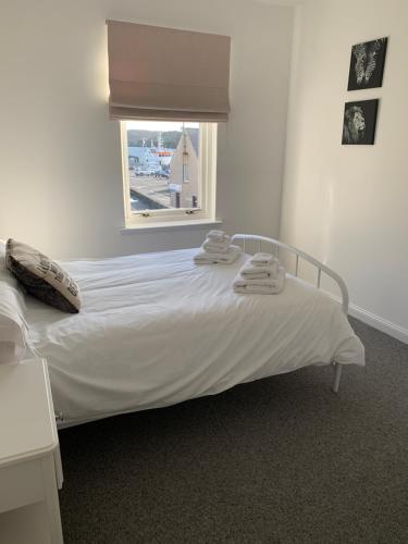 un letto bianco in una stanza con finestra di No.10 a Stornoway