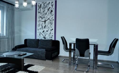uma sala de estar com um sofá, uma mesa e cadeiras em Nidius Apartment em Debrecen