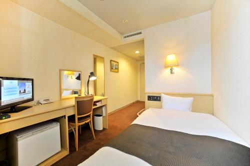 a hotel room with a bed and a desk with a computer at Yamagata Kokusai Hotel in Yamagata