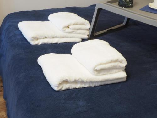 4 serviettes blanches assises au-dessus d'un lit dans l'établissement Apartament na Osiedlowej, Ciechocinek, à Ciechocinek