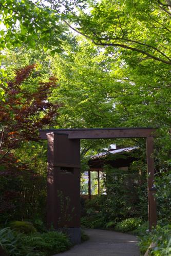 a wooden archway in a garden with trees at Yufuin Bettei Itsuki in Yufuin