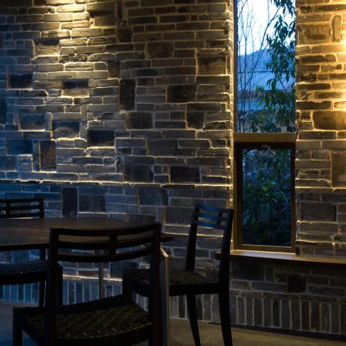 a table and chairs in a room with a brick wall at Yufuin Bettei Itsuki in Yufuin