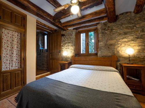 a bedroom with a bed and a stone wall at CASA RURAL CRUZ - Self check-in in Boltaña