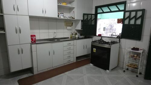 a kitchen with white cabinets and a black refrigerator at Hospedaria Casa Verde in Lençóis