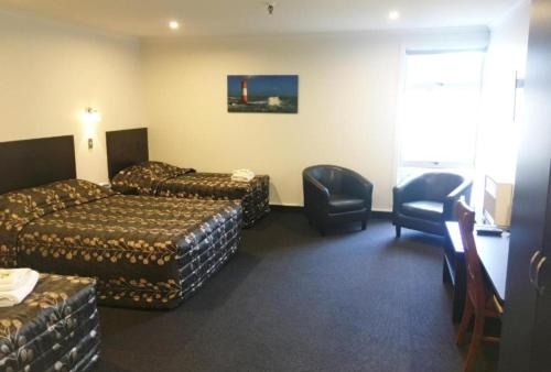 a hotel room with two beds and a television at Leviathan Hotel in Dunedin