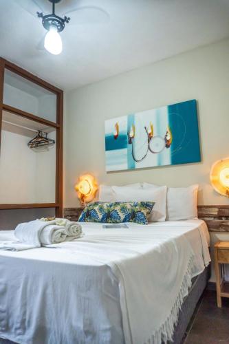 a bedroom with a large white bed with two lamps at Anacã Pousada in Arraial d'Ajuda