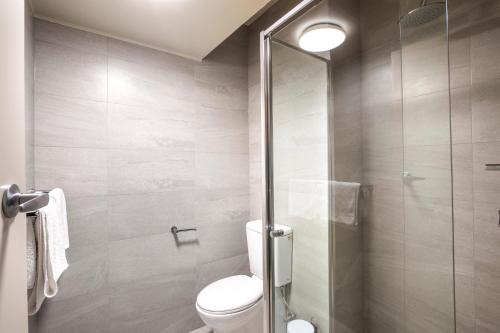 a bathroom with a toilet and a glass shower at Nightcap at Manhattan Hotel in Ringwood
