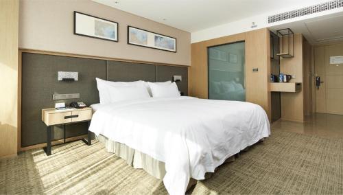 a hotel room with a large white bed and a desk at Zenith Hotel-Near Train Station & The Mixc in Xiamen