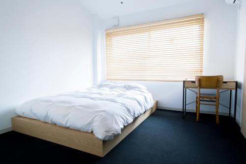 a bedroom with a bed and a desk and a window at Yado Arashiyama in Kyoto