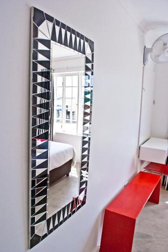 a mirror hanging on a wall with a red bench at Funky Town in Jeffreys Bay