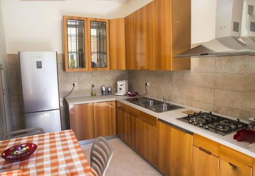 cocina con armarios de madera y nevera blanca en LE PITTURE casa di campagna, en Filiano