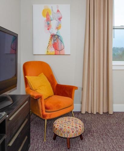 a living room with an orange chair and a ottoman at The Dundee - A Trace Hotel in Dundee