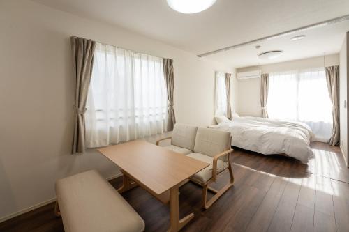 a bedroom with a table and a bed and a table and chairs at Beans Stay Ishibiki in Kanazawa