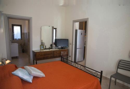 a bedroom with an orange bed and a desk and a refrigerator at LE PITTURE casa di campagna in Filiano
