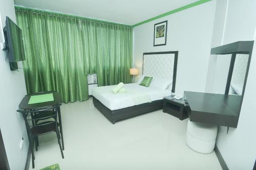 a bedroom with a bed and a desk and a television at GREEN BANANA BUSINESS HOTEL in Davao City