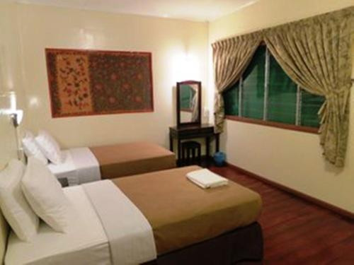 a hotel room with two beds and a window at Mile 36 Lodge in Kundasang