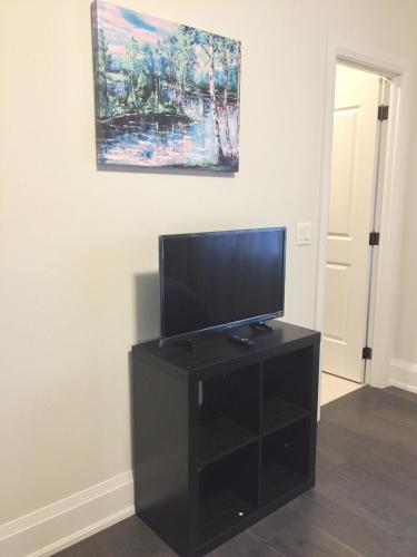 a flat screen tv on a black stand in a room at Comfortable private space in Pickering