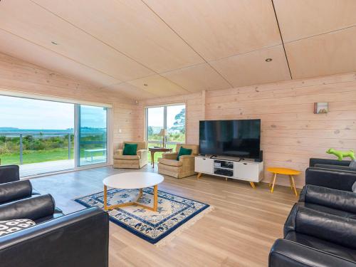 a living room with a tv and a couch and chairs at Beachfront Escape - Snells Beach Holiday Home in Snells Beach