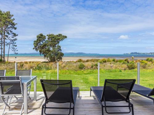 a table and chairs on a deck with a view of the beach at Beachfront Escape - Snells Beach Holiday Home in Snells Beach