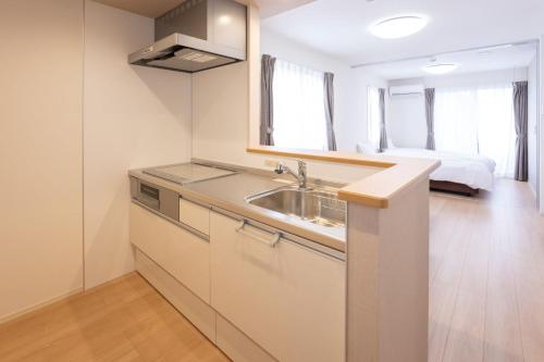 a kitchen with a sink and a bed in a room at Beans Stay Ishibiki in Kanazawa