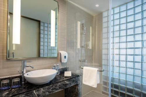 ein Bad mit einem Waschbecken, einem Spiegel und einer Dusche in der Unterkunft Holiday Inn Express Shanghai New Jinqiao, an IHG Hotel in Shanghai