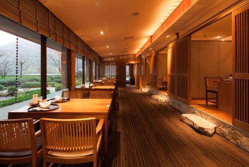 a restaurant with wooden tables and chairs and large windows at ANA Crowne Plaza Matsuyama by IHG in Matsuyama